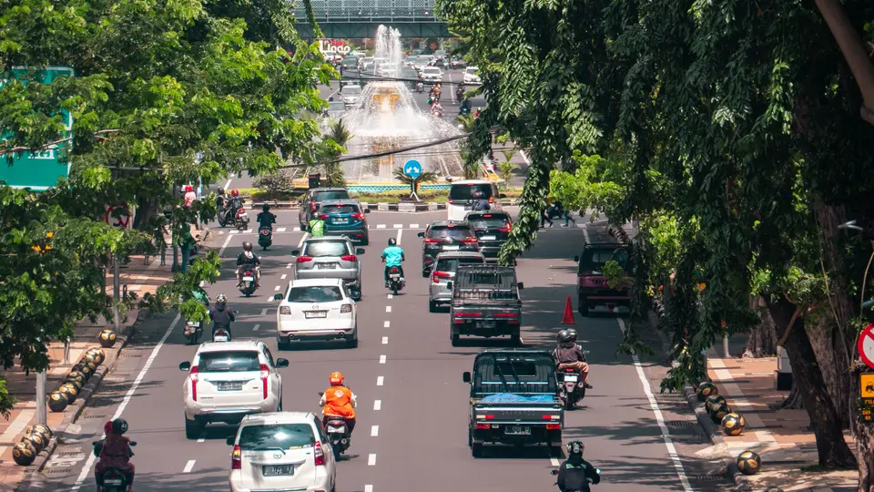 Foto ilustrasi jalan raya di Kota Denpasar dengan pepohonan di kedua sisi